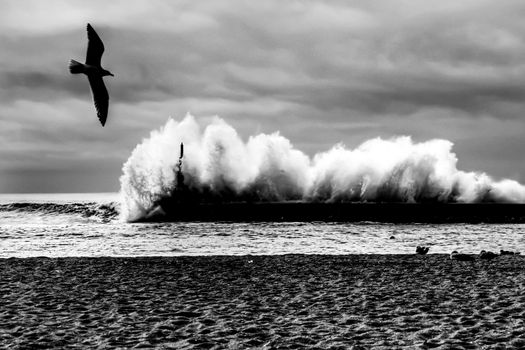 Giant waves breaking on the breakwater and the lighthouse on Aguda Beach, Miramar, Arcozelos town