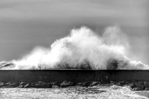 Giant waves breaking on the breakwater on Aguda Beach, Miramar, Arcozelos town