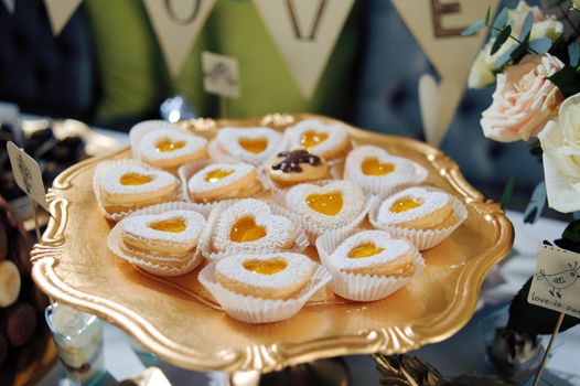 fruit tartlets on a golden tray, festive table with desserts.