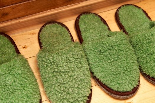 Felt green slippers for guests on the wooden floor in the hallway. Close up