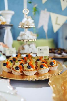 fruit tartlets on a golden tray, festive table with desserts.