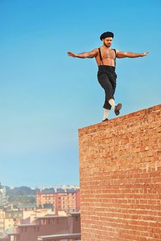 Balancing high. Shot of a shirtless retro male builder walking balancing on a brick wall