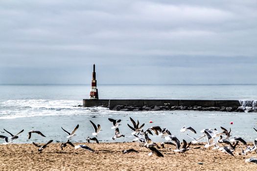 Breakwater and lighthouse in a cloudy day of Aguda Beach, Miramar, Arcozelos town