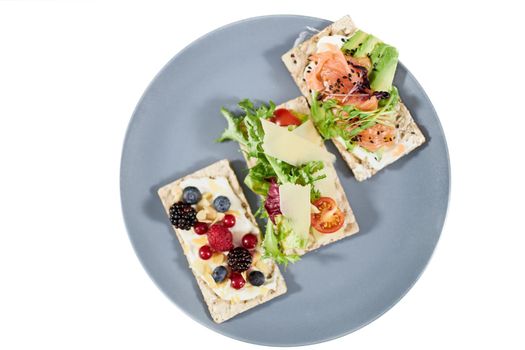 Top view close up of three diet breads with salmon,avocado,greens,tomatoes, and fresh berries on white background. Concept of delicious snacks with seafoods in restaurant or home. 