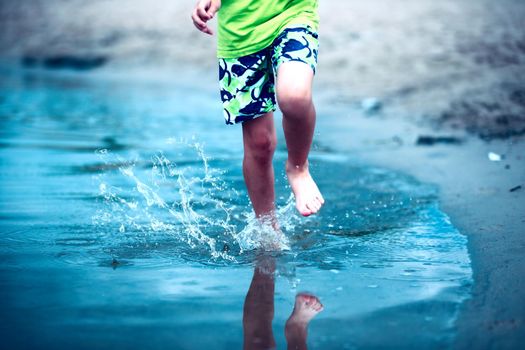 Children's feet run through the water spraying water.
