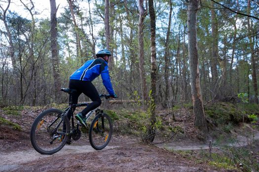 rides mountain bike in spring forest near utrecht in holland