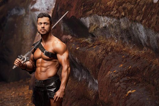 Portrayal of strength. Portrait of a strong handsome gladiator standing with a sword outdoors copyspace