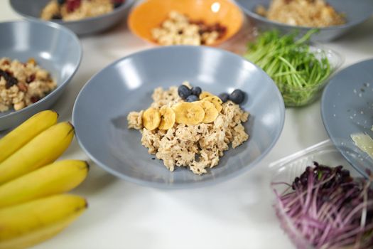 Close up of tasty and healthy porridge with fresh fruits in beautiful blue plate. Concept of process cooking delicious dish at home with tasty ingredients and fresh vegetables and fruits.