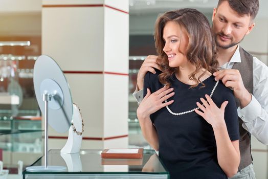 You look gorgeous Happy young couple trying on a pearl necklace at the jewelry store cpyspace anniversary sale shopping buying consumerism wealthy wellbeing people customers love couple concept.