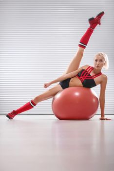Vertical shot of a beautiful fitness woman in workout gear lying on a fit ball stretching her legs flexible flexibility gymnastics gymnast athlete active sexy lifestyle healthy vitality people concept.