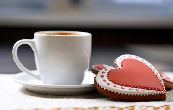 Hungry for sweets. Closeup of a glazed Valentine s day cookie and a cup of delicious beverage at the local cafe