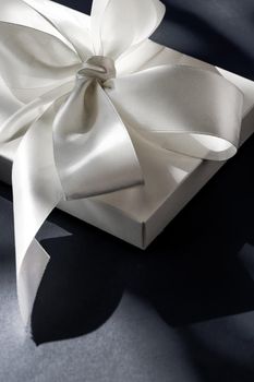 Anniversary celebration, shop sale promotion and luxe surprise concept - Luxury holiday white gift box with silk ribbon and bow on black background, luxe wedding or birthday present