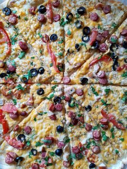 Sliced large pizza lies on the table close-up.