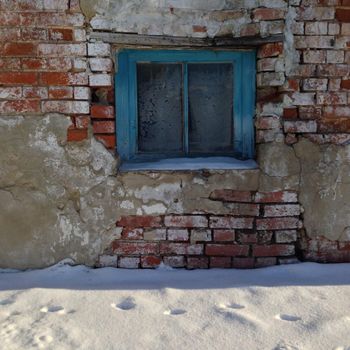 Old building with brick wall and window. Winter and snow, Russia.