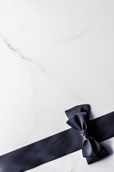 Holiday gift, decoration and sale promotion concept - Black silk ribbon and bow on marble background, flatlay