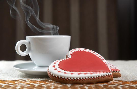 For you. Coffee steaming in a cup on the table next to two gingerbread heart shaped cookies