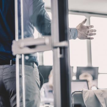 Businessman making a presentation at office. Business executive delivering a presentation to his colleagues during meeting or business training. View through glass. Business and entrepreneurship.