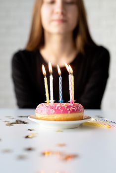 Birthday party. Teenager birthday girl blowing candles on the donut