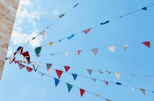 Several strings of multicolored bunting flags against blue sky