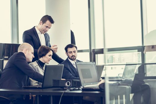 Workplace in modern office with business people brainstorming. Businessman working on laptop during the meeting.