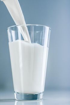 Dairy, healthy nutrition and breakfast concept - World Milk Day, pouring into glass on marble table