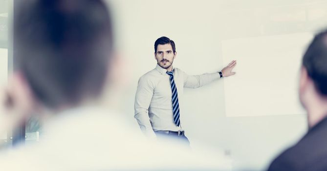 Business man making a presentation at office. Business executive delivering a presentation to his colleagues during meeting or in-house business training, explaining business plans to his employees.