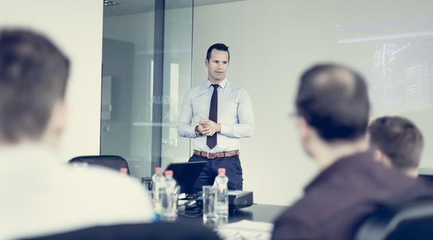 Business man making a presentation at office. Business executive delivering a presentation to his colleagues during meeting or in-house business training, explaining business plans to his employees.