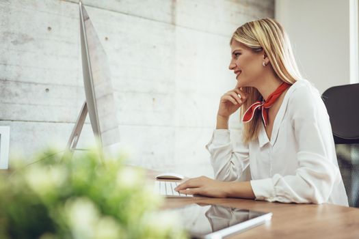 Young beautiful successful female entrepreneur working on computer at the office.