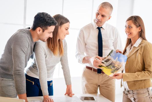 Young couple consult with two real estate agents about buying new house.