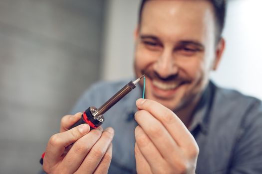 Close-up of a successful engineer or technician focused on soldering copper wire. Selective focus.