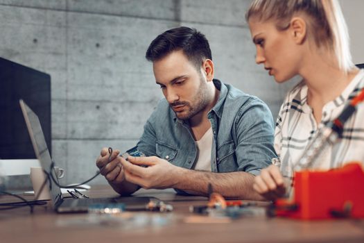 Two young business partners technician focused on the repair of electronic equipment.