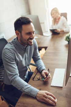 Young handsome successful businessman working on computer at the office.