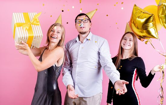 Birthday party. Three friends in birthday hats celebrating birthday party over pink background