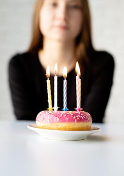 Birthday party. Teenager birthday girl blowing candles on the donut