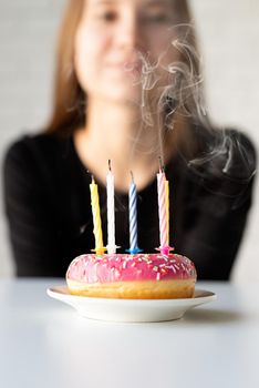 Birthday party. Teenager birthday girl blowing candles on the donut