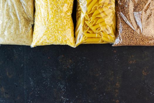 Food supply quarantine food crisis isolated on black concrete background. Rice, pasta, corn flakes, buckwheat. The concept of food delivery, donation, charity. Copyspace.