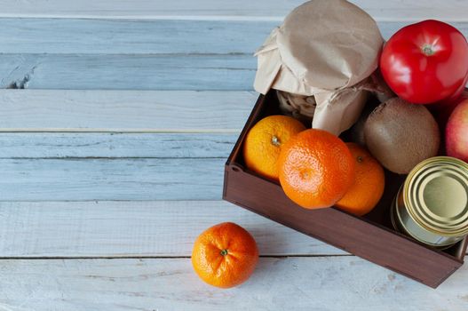 The courier delivered a box of food during the coronavirus pandemic. In the box are fruits, vegetables, canned goods. A charity concept. Copy space.