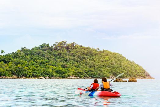 Two woman tourists are mother and daughter travel by boat with a kayak under sunlight of summer at Ko Lipe enjoy the beautiful nature the sea and island in morning, Tarutao National Park, Satun, Thailand