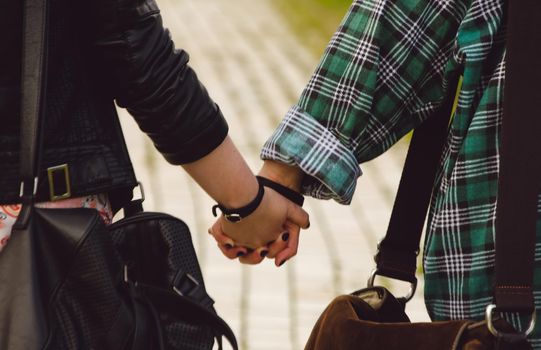 Girlfriends hold hands and walk in the park, a young lesbian couple walk outdoors