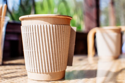 Disposable paper coffee cup with holder on table in cafe with wooden stirrer.Environmentally friendly lifestyle.Zero Waste,Save The Planet,Earth Day,No Plastic,Recycling Concept