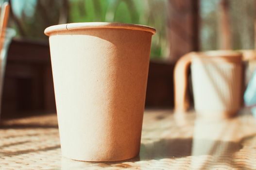 Disposable paper coffee cup on table in cafe with wooden stirrer.Environmentally friendly lifestyle.Zero Waste,Save The Planet,Earth Day,No Plastic,Recycling Concept