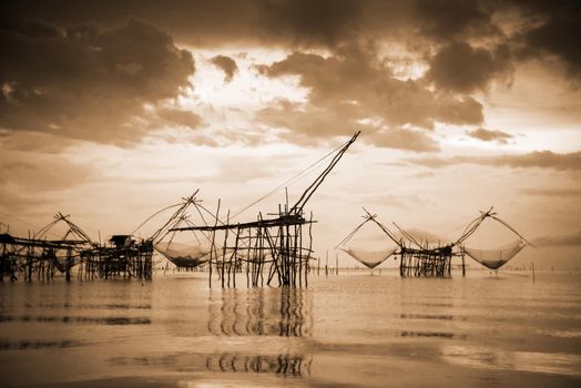 Old photo in sepia warm two tone vintage style, landscapes of Songkhla Lake and fishing square dip net is a local fishing tool rural lifestyle at Pakpra canal, Baan Pak Pra, Phatthalung in Thailand