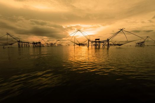 Beautiful nature landscape colorful golden light of the morning sky at sunrise and native fishing tool rural lifestyle at Pakpra canal, Songkhla Lake, Baan Pak Pra, landmark of Phatthalung, Thailand