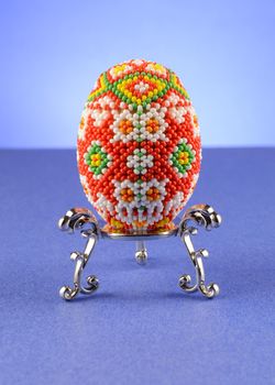 Some beautiful bead work decorated into a pattern around a chicken egg.