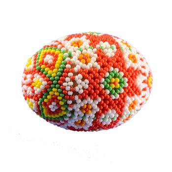 Closeup of some beautiful bead work designed over a chicken egg and isolated over a white background.