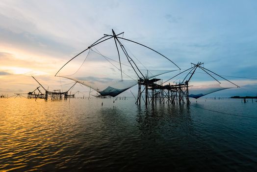 Beautiful nature landscape golden light of the morning sky at sunrise and native fishing tool rural lifestyle at Pakpra canal, Songkhla Lake, Baan Pak Pra is a famous landmark of Phatthalung, Thailand