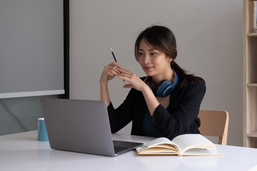 A woman listens to an instructional webinar on her laptop while wearing headphones