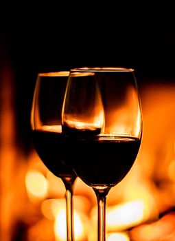 Two glasses of red wine on the background of fireplace lights. Christmas holiday concept