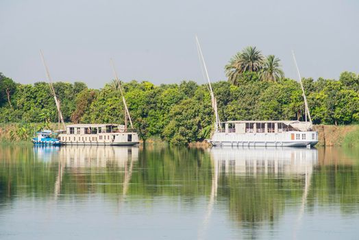 Large luxury traditional Egyptian dahabeya river cruise boat moored on the Nile bank