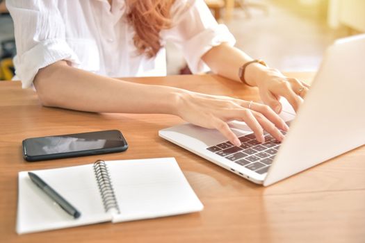 Young businesswoman using laptop on her desk at the workplace, closeup